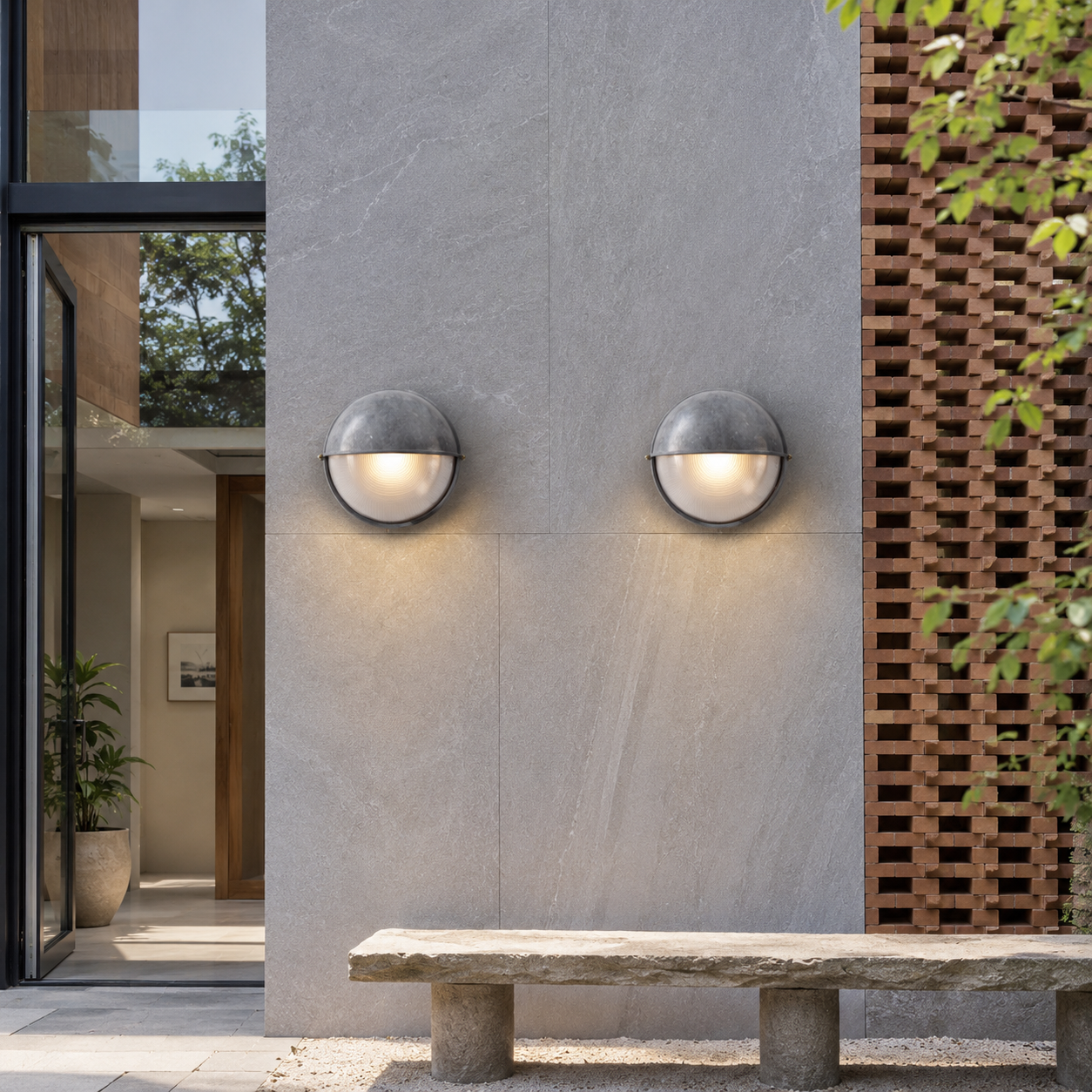 Modern outdoor wall lights on a gray stone wall with a bench and plants in the foreground.